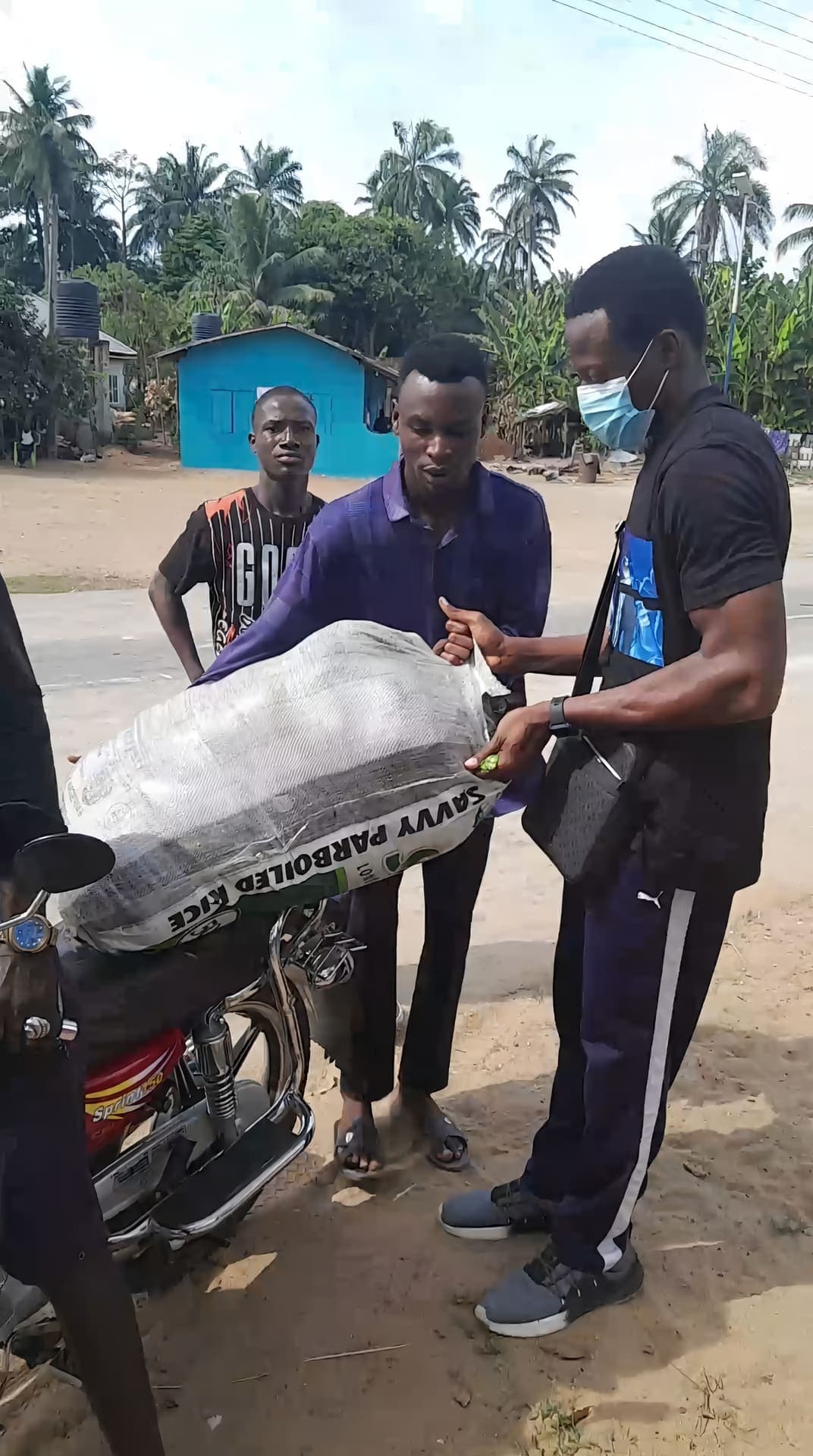 Volunteers loading a sack of rice onto a motorcycle during the Eku outreach