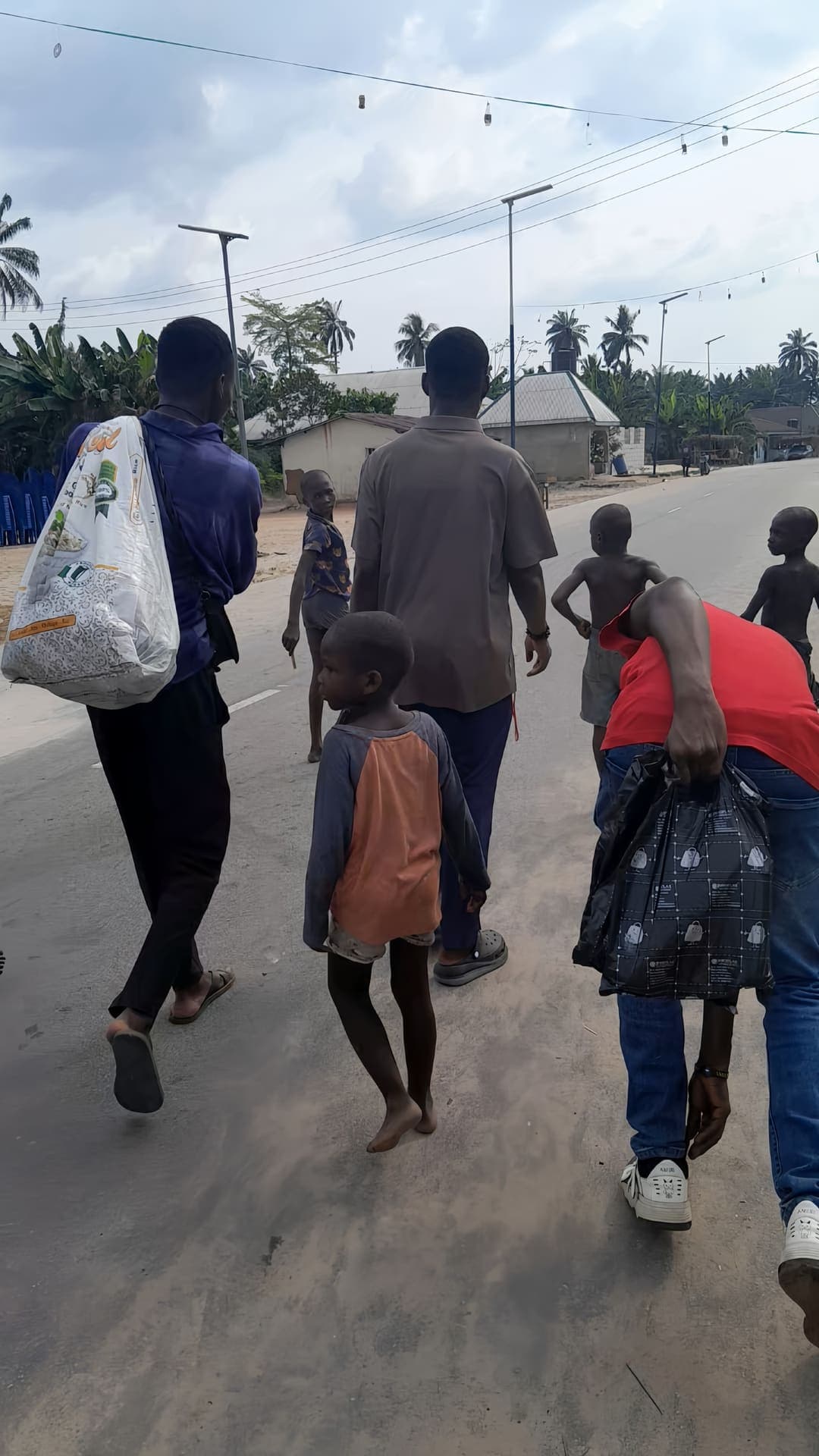 Volunteers walking through Eku with relief supplies, children leading the way, December 2025 outreach